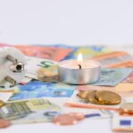 a lighted candle on top of a paper money
